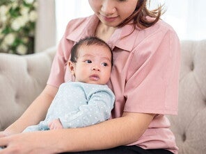 Mom holding newborn baby on couch