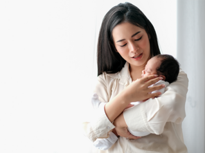 Photo of Asian mom carrying her infant upright to help with newborn hiccups