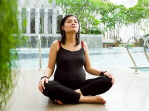 Pregnant woman in black doing yoga by the pool. Pregnant woman in black doing yoga by the pool.