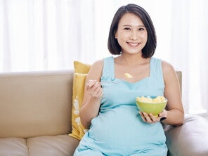 Teaser_Image Young and smiling Asian pregnant woman eat a bowl of fruits good for pregnancy.