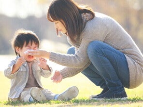Asian mom comforts her little boy to help his emotional regulation as he cries outdoors.