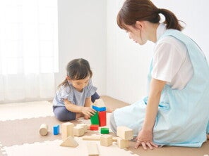 A little Asian girl and her green flag yaya playing with building blocks at home.