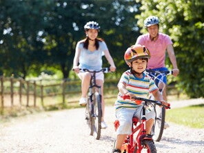 Young Asian family of three go biking at a park to prevent child obesity. Young Asian family of three go biking at a park to prevent child obesity.