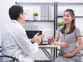 A pregnant Asian woman talking to her doctor, learning about the 4 stages of labor A pregnant Asian woman talking to her doctor, learning about the 4 stages of labor