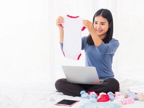 A young 8 weeks pregnant Asian woman shopping online for her baby
