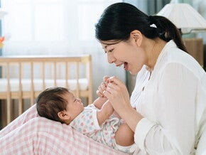 A young Asian woman sings a Filipino nursery rhyme or lullaby to a baby lying on her lap. A young Asian woman sings a Filipino nursery rhyme or lullaby to a baby lying on her lap.