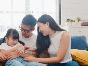 An Asian couple with their little girl on the sofa at home, a picture of family love.