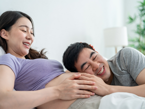An Asian husband putting his ear to his 14 weeks pregnant wife’s belly in the bedroom. An Asian husband putting his ear to his 14 weeks pregnant wife’s belly in the bedroom.