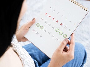 An Asian woman holding a calendar marked to show her menstrual cycle and fertile window