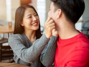 Young Asian woman pinches her partner's cheeks as they talk responsible parenthood. 