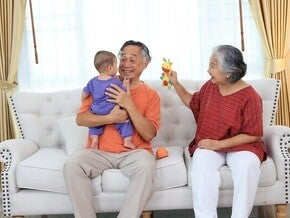 Happy Asian lolo and lola taking care of their toddler grandchild and using grandparenting tips to be better at co-parenting.