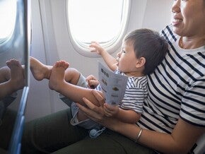 Asian mom traveling with baby on her lap in the plane.