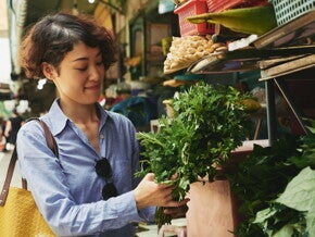 Asian woman buying vegetables at the wet market and thinking of budget ulam ideas to fit ₱500 