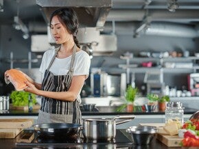Young Asian woman prepping iodine-rich foods like fish in the kitchen. 