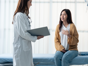 Young Asian woman talking to her doctor about her pregnancy spotting color and flow.