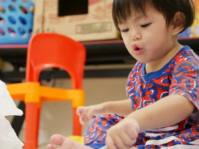 Asian 18-month-old baby scribbles with a pen during playtime.