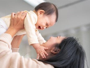 Asian baby girl grabs her mom's face as her mom lifts her Asian baby girl grabs her mom's face as her mom lifts her