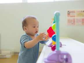 Asian baby plays appropriate toy for a 1-year-old at home.
