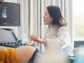 Asian doctor performs one of the types of ultrasounds in pregnancy.