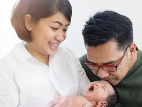Asian mom and dad holding their newborn baby, thinking of baby boy names with meaning