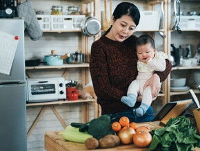 Asian mom and son looking at table of vegetables