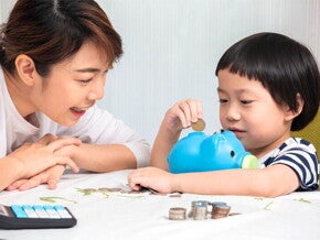 Asian mom and son putting coins in piggy bank Asian mom and son putting coins in piggy bank