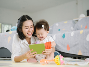 Asian mom and toddler daughter happily reading