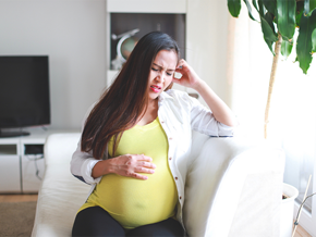 Asian pregnant woman winces in pain due to heartburn Asian pregnant woman winces in pain due to heartburn