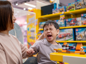 Asian toddler becomes short-tempered while in a toy store with mom Asian toddler becomes short-tempered while in a toy store with mom