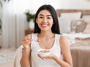 Asian woman eats a bowl of oatmeal
