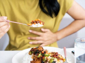 Close-up pic of an Asian woman’s hand holding a spoon of spicy food for pregnant women.
