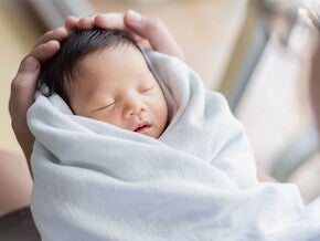 Closeup of healthy newborn in a swaddle being held by the father. Closeup of healthy newborn in a swaddle being held by the father