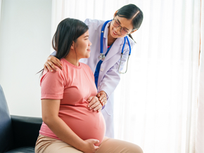 Doctor checks up on female patient who is 35 weeks pregnant.