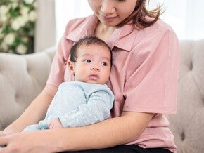 Mom holding newborn baby on couch