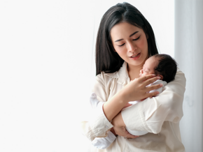 Photo of Asian mom carrying her infant upright to help with newborn hiccups
