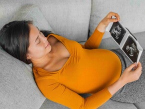 Pregnant Asian woman holding an ultrasound image. Pregnant Asian woman holding an ultrasound image.