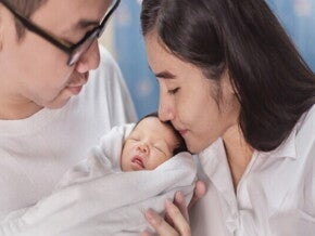 Asian newborn baby yawns as they lie in a bassinet at a maternity hospital.