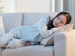 Recognizing Early Signs of Pregnancy Young Asian woman falls asleep on the sofa, exhibiting an early sign of pregnancy.