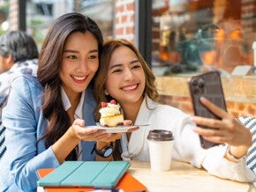Two Asian working moms take a selfie after meeting for dessert during lunch break.
