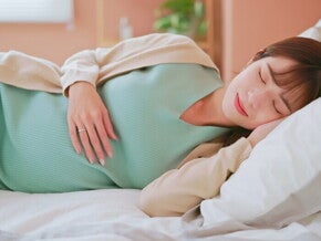 Young Asian mom at Week 20 of pregnancy sound asleep in bed.