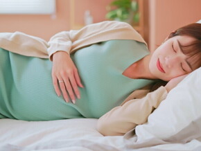 Young Asian mom at Week 20 of pregnancy sound asleep in bed.