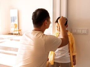 Asian dad marks his son's height on the wall to record growth milestone.