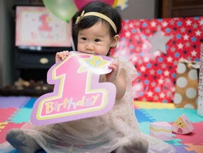 Little Asian baby girl celebrating her first birthday with a birthday party. 