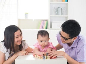 Young Asian parents spending quality time and playing with their little girl in the living room.