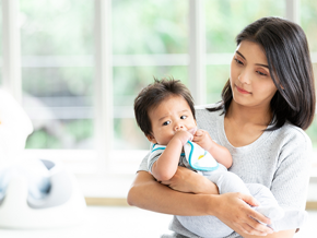 Young Asian mom carrying her baby and thinking about how to increase breast milk supply.