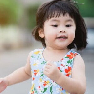 Asian female toddler runs in the street during summertime. Asian female toddler runs in the street during summertime.