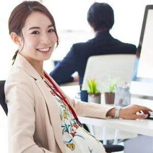 Pregnant Asian takes a break from working on her computer at an office. Pregnant Asian takes a break from working on her computer at an office.