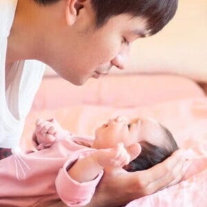 Young Filipino dad talks to his newborn while putting them down. Young Filipino dad talks to his newborn while putting them down.
