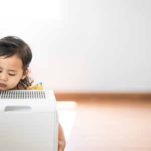 A photo of a little girl breathing in clean air from an air purifier at home A photo of a little girl breathing in clean air from an air purifier at home