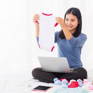 A young 8 weeks pregnant Asian woman shopping online for her baby A young 8 weeks pregnant Asian woman shopping online for her baby